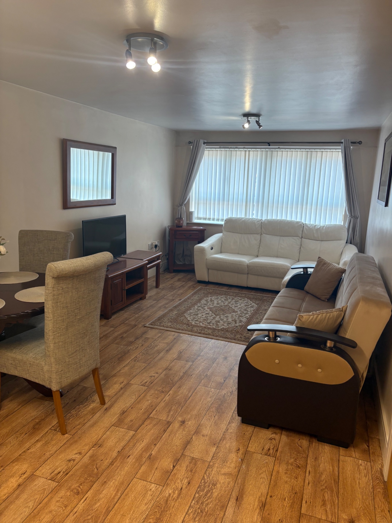Clean serviced apartment lounge with sofa, dining table and tidy kitchen area